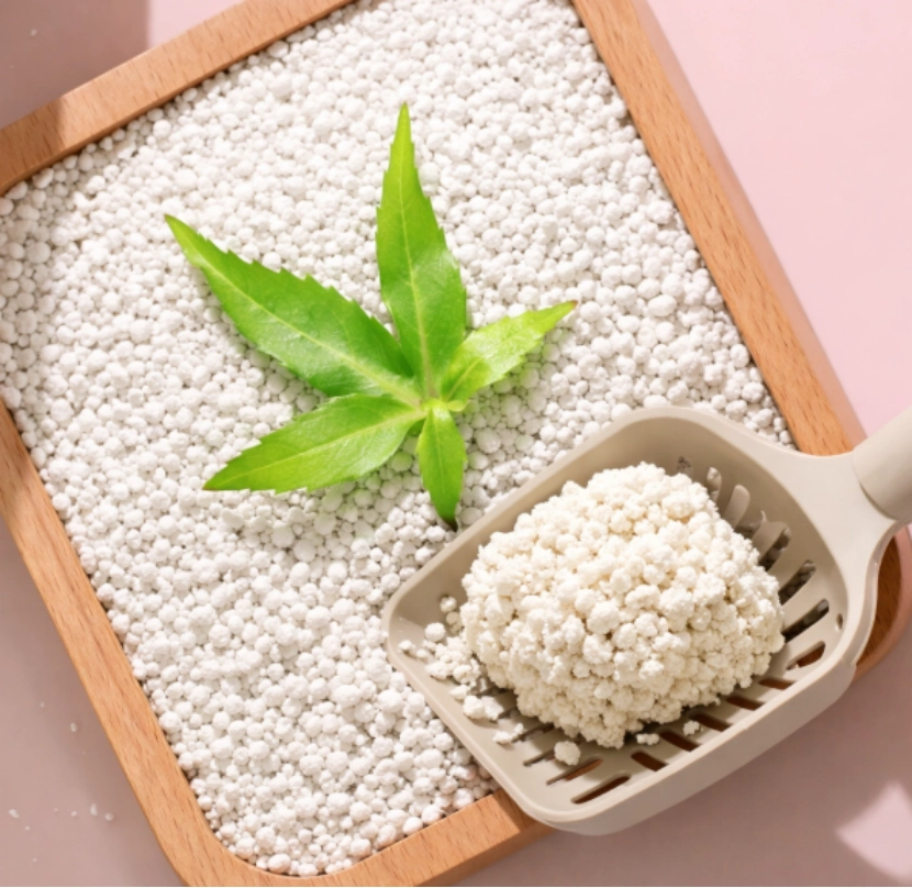 A close-up of cat litter with a scoop and a green leaf