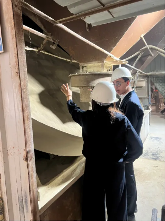 Two professional buyers in hard hats inspecting production equipment at a bulk cat litter manufacturing factory